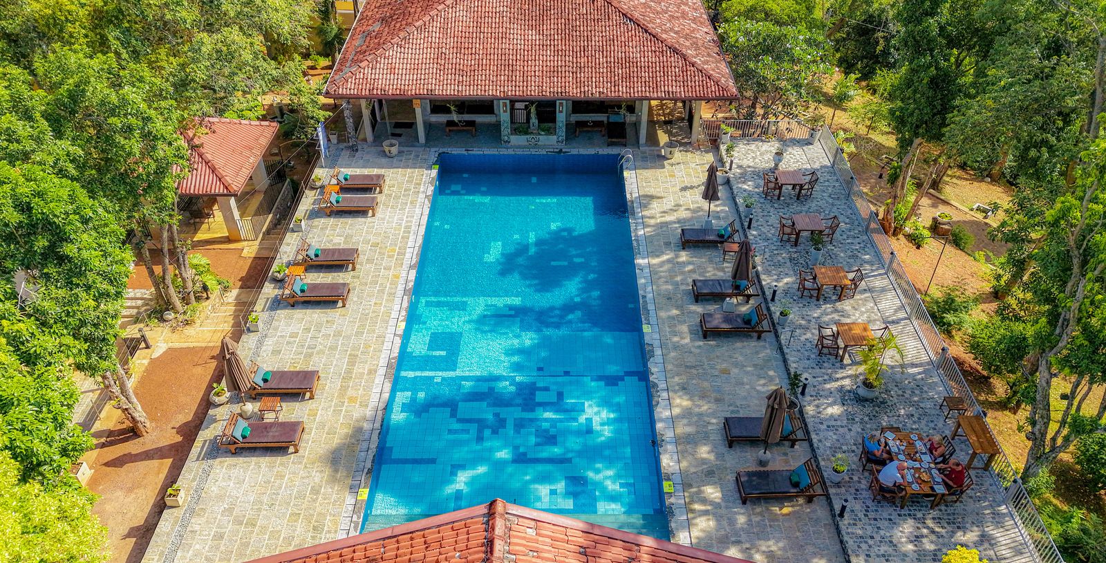 The pool from above, lined with loungers and a terrace where guests are having breakfast